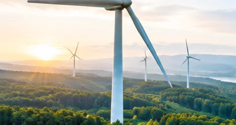 Wind turbines on forested hills at sunset